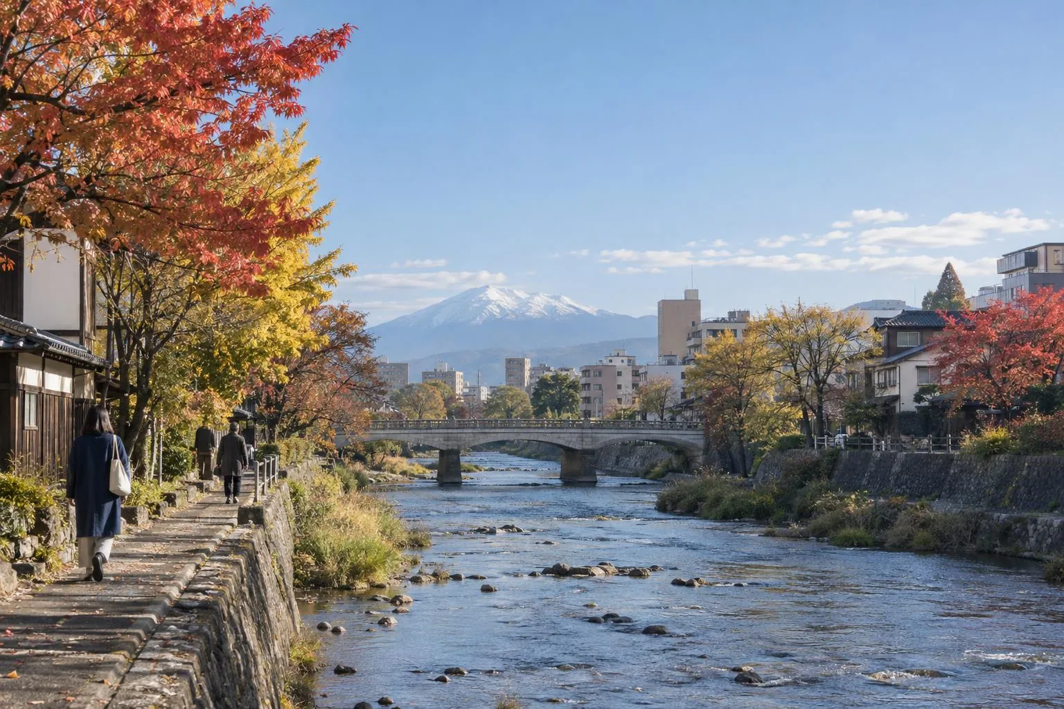 秋の中津川。石の護岸と橋、遠くに岩手山
